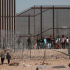 Ciudad Juárez. Migrantes se abren paso a un costado de la cerca de alambres en la frontera que divide a México de los EE. UU.