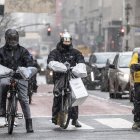 Personas en bicicletas de reparto se abrigaron contra la nieve que caía durante una tormenta de invierno en Nueva York, Nueva York, EE.UU., 19 de enero de 2024.