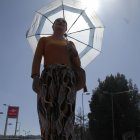 Las personas se cubren del sol con vestimentas largas y sombrilla.