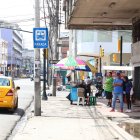 Espacios. Usuarios de buses se protegen de los rayos solares en los exteriores de un inmueble en el centro de Guayaquil mientras esperan por sus unidades.