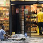 Desigualdades. Una persona en condición de calle espera ayuda de transeúntes afuera de un minimercado.