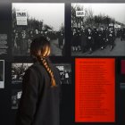 Una mujer junto a una fotografía impresa de Missak Manouchian (I), en la exposición "Los extranjeros en la resistencia en Francia", en del Museo de la Shoáh, en París