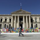 Personas caminan frente al Palacio Nacional, en el centro de San Salvador.
