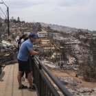 Personas observan hoy viviendas destruidas en el sector de Achupallas, afectado por incendios forestales de Viña del Mar, Región de Valparaiso (Chile). El número de fallecidos en los devastadores incendios que azotan la región de Valparaíso, a 100 kilómetros al oeste de Santiago, aumentó a 99, de los cuales solo 32 han podido ser identificados, informó este domingo el Servicio Médico Legal (SML) de Chile. EFE/ Adriana Thomasa