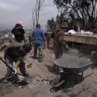 Un grupo de personas retiran escombros de una casa destruida en el sector de Achupallas, afectado por los incendios forestales, en Viña del Mar