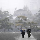 Unas personas caminan durante las nevadas en los jardines que rodean el Palacio Imperial en Tokio, Japón, el 5 de febrero de 2024.