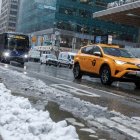 Nueva York. Varios vehículos circulan por la Sexta Avenida mientras cae nieve.