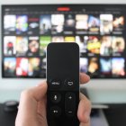 EL STREAMING - MANO SOSTENIENDO UN CONTROL REMOTO FRENTE A LA TELEVISIÓN |