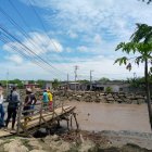 Un grupo de personas observa los restos de un puente de madera que cruzaba sobre el río Atravezado, en Libertador Bolívar, Santa Elena.
