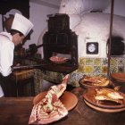 Un cocinero introduce una fuente en el horno de asar.