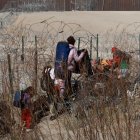 Migrantes intentan cruzar la cerca de alambres en la frontera que divide a México de los Estados Unidos.