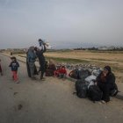Un grupo de palestinos descansa tras cruzar desde el norte de la Franja de Gaza hacia el sur por la carretera Al Rashid, el 26 de febrero de 2024.