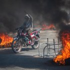Una persona se transporta en motocicleta con incendios alrededor, este viernes en Puerto Príncipe (Haití).