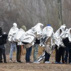 Migrantes se alinean mientras se preparan para ser recogidos por agentes de la Patrulla Fronteriza en Eagle Pass