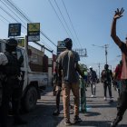 Manifestantes contra la situación política y social de Haití tras la renuncia del primer ministro Ariel Henry pasan junto a un carro policial.