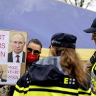 Una persona sostiene un cartel de protesta mientras los rusos esperan en fila para votar en la embajada rusa en La Haya, Países Bajos