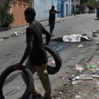 Transeúntes pasan junto al cadáver calcinado de una persona en la calle este miércoles en Puerto Príncipe (Haití).