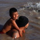 Un migrante con su hijo en la espalda cruza el Río Bravo, en la frontera que divide a México de los Estados Unidos