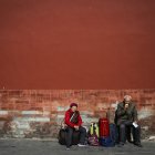 Una pareja de ancianos espera junto a su equipaje durante una visita a la Ciudad Prohibida en Pekín