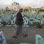 Un partidario hutí pasa junto a las tumbas de los combatientes hutíes en un cementerio dedicado a aquellos que murieron en la prolongada guerra del país, antes del noveno aniversario de la intervención saudí en la guerra de Yemen, en Saná, Yemen.