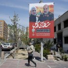 Una mujer pasa junto a un cartel que muestra fotografías del general de brigada iraní Mohammad Reza Zahedi (R), comandante de los Quds del Cuerpo de la Guardia Revolucionaria Islámica (CGRI)