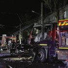 Rescatistas ucranianos trabajan cerca de su vehículo dañado en la escena de un ataque nocturno ruso con drones contra un edificio residencial en Járkov.