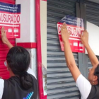 Medida.- Dos miembros de Arcsa pone el sello de clausura en la puerta de un supermercado en Ibarra.