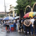 Los electores hacen fila en los exteriores de los recintos electorales cubriéndose de las lluvias con paraguas