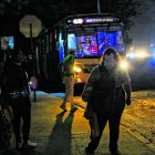 Los pasajeros esperan los buses en una oscuridad tenebrosa.