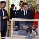 El presidente Xi Jinping (i) y Emmanuel Macron, miran los regalos durante el intercambio de obsequios entre las naciones, en el Palacio Presidencial del Elíseo en París.