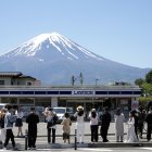 Turistas hacen fotografías de la tienda de la cadena Lawson con el Monte Fuji al fondo, en Fujikawaguchiko, al norte del Monte Fuji, Japón, el 10 de mayo de 2024.