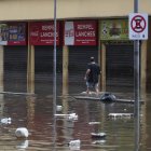 Un hombre camina en una calle inundada de agua y basura en un centro comercial este lunes, en Porto Alegre (Brasil).