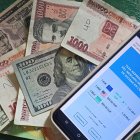 Se muestran billetes junto a un celular con la aplicación del diario digital independiente El Toque,