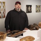 Timothy, de los Wiradjuri, posa junto a varias piezas de arte.