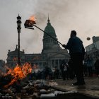 Un hombre quema una caja durante enfrentamientos entre la policía y personas que protestan a las afueras del Senado.