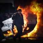 Un hombre es visto caminar frente a una carro en llamas en una protesta a las afueras del senado durante un debate este miércoles, en Buenos Aires (Argentina).