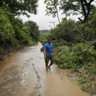 Un hombre camina por un sendero inundado debido a fuertes lluvias, el 21 de junio del 2024, en Soyapango.