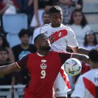 El delantero canadiense Cyle Larin (L) y el defensor peruano Miguel Araujo (R) desafían el balón durante la primera mitad del partido.