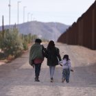 Una familia camina a lo largo del muro fronterizo de Estados Unidos buscando a la Patrulla Fronteriza estadounidense para entregarse para su procesamiento.