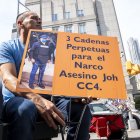 Un hombre sostiene una pancarta que pide "3 cadenas perpetuas al expresidente hondureño Juan Orlando Hernández", frente al tribunal federal de Manhattan en Nueva York.