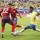 El delantero brasileño Vinicius Junior (d) intenta pasar por el defensor costarricense Haxzel Quiros (i) y el centrocampista costarricense Alejandro Bran (C) durante la segunda mitad de la CONMEBOL.