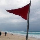 una bandera roja en la playa que indica oleaje agitado y fuertes corrientes debido a la proximidad de la tormenta tropical "Beryl", en Cancún.