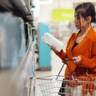 Una joven consulta la información de un cartón de leche en un supermercado.