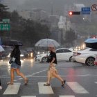 Varias personas cruzan una calle en Seúl (Corea del Sur), en medio de la lluvia debido a la influencia del tifón Gaemi que avanza hacia la Península de Corea.