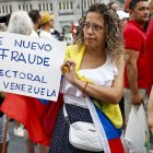 Una mujer sostiene una pancarta en la manifestación convocada por la oposición venezolana un día después de las elecciones en el país, este lunes en Madrid.