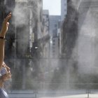 Tokio. Una mujer se refresca en un chorro de agua en un día caluroso.