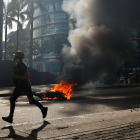 Un manifes.tante corre durante enfrentamientos entre opositores y miembros de la Guardia Nacional Bolivariana (GNB)