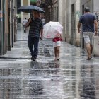 Varias personas caminan bajo la lluvia por una calle del centro de Valencia.
