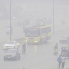 Personas viajan en coches y motocicletas bajo la nube de contaminación en Lahore.