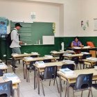 Una profesora prepara clase en el salón de una escuela previo al inicio de clases